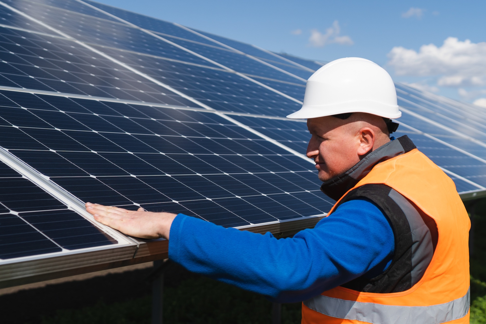 Solar plant worker inspecting photovoltaic panels for damage